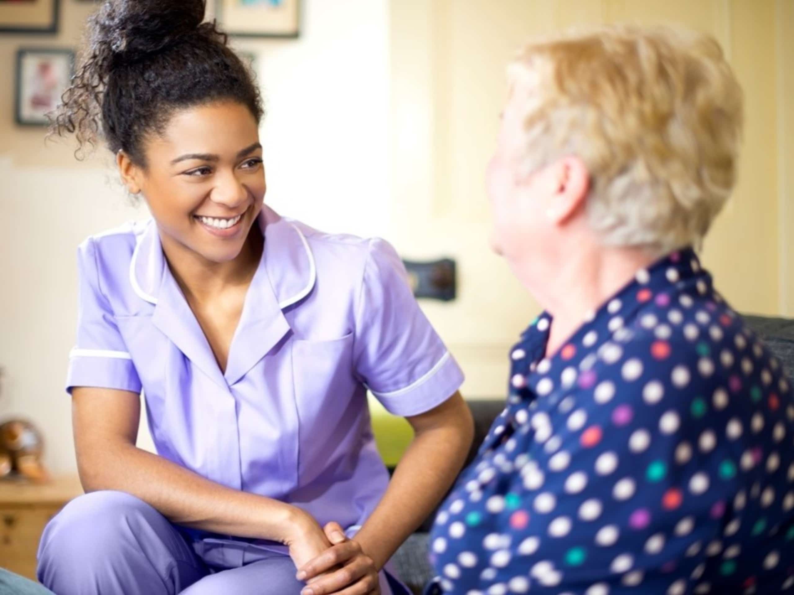 a women working in adult care sitting down with an elderly lady