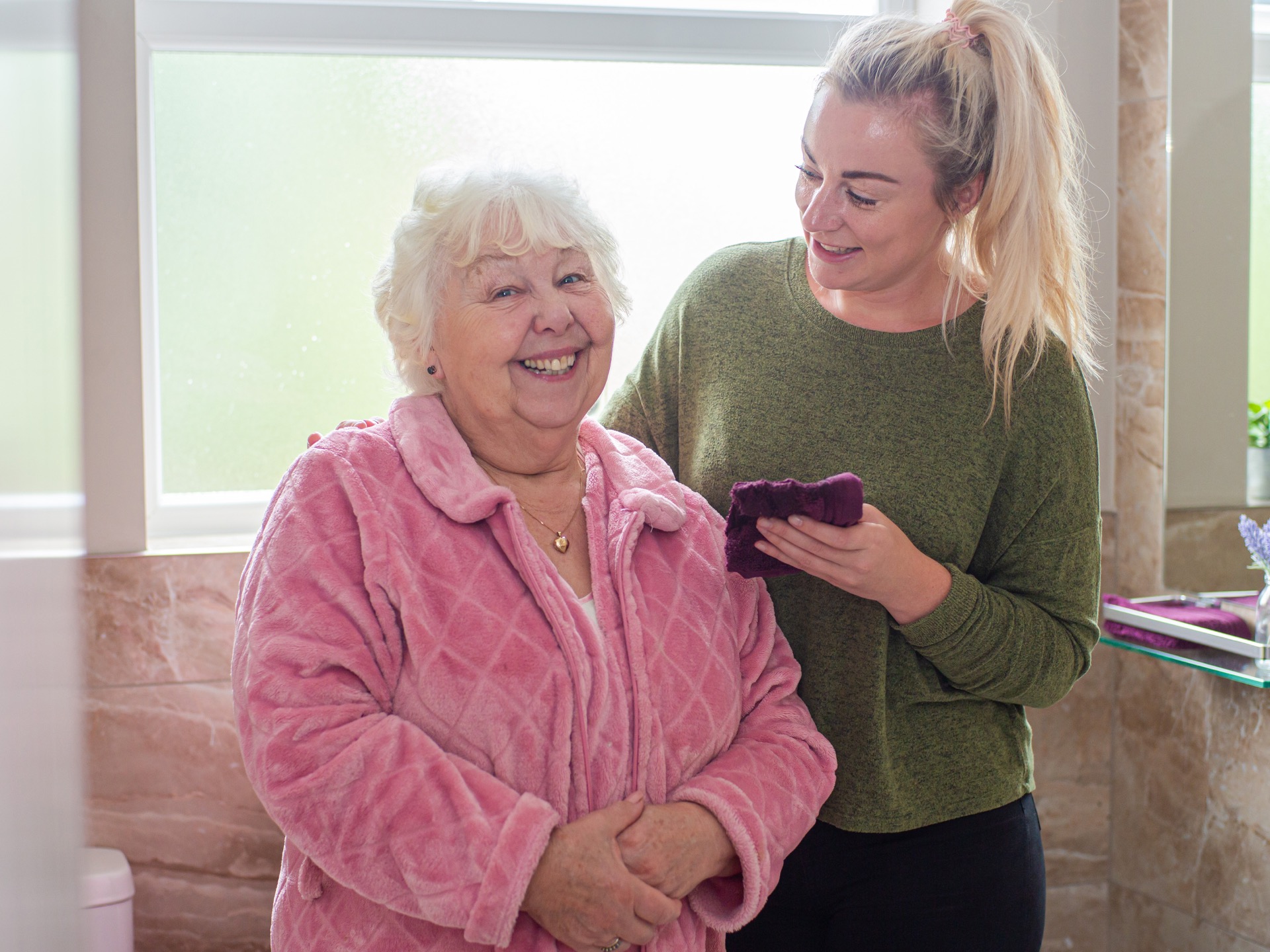 elderly lady smiling next to a personal care assistant