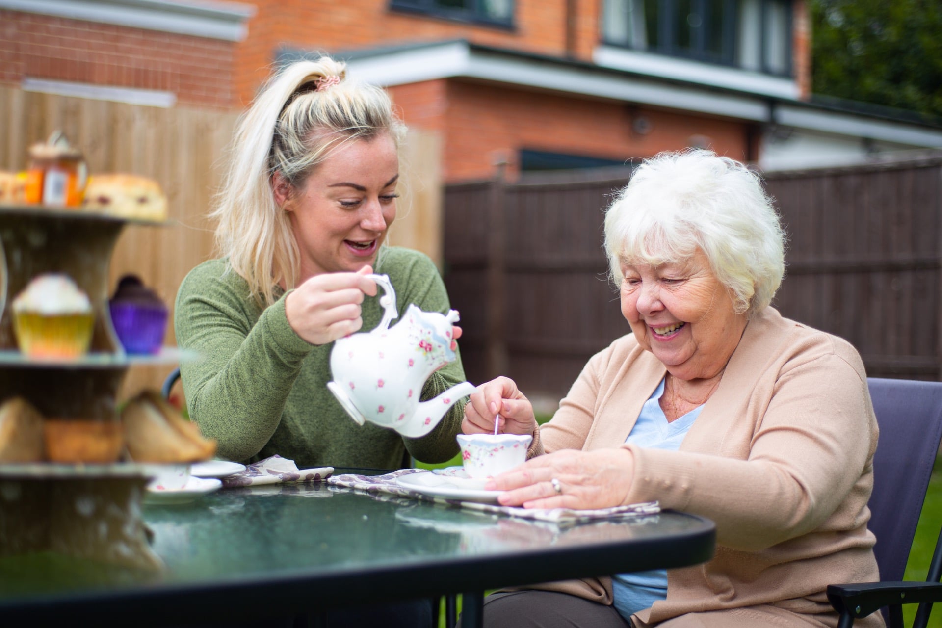 a women working in respite care pouring tea for an elderly lady