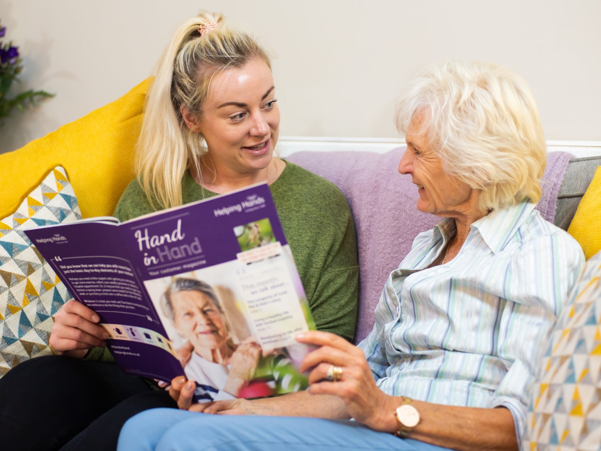 a women working in companion care reading a book to an elderly lady