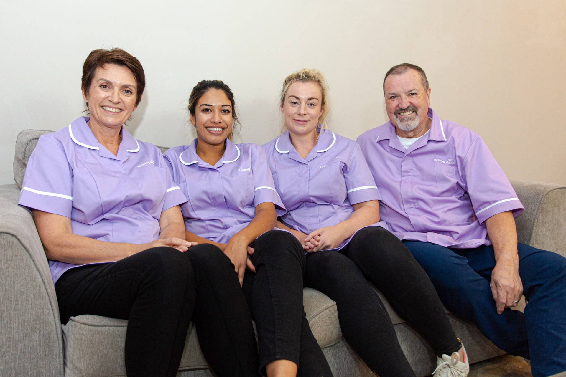 men and women who provide live in care sitting on the sofa and smiling
